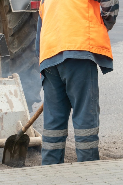 Repair of city roads and replacement of worn asphalt concrete\
pavement a worker with a shovel throws concrete into a pit to\
eliminate damage to the roadway