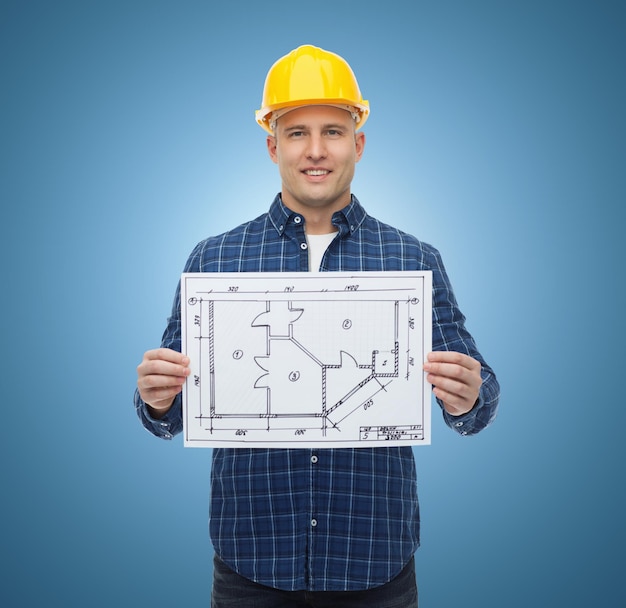 Repair, construction, building, people and maintenance concept - smiling male builder or manual worker in helmet with blueprint over blue background
