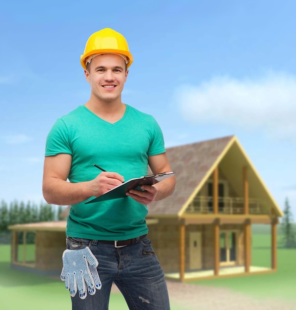 repair, construction and maintenance concept - smiling man in helmet with clipboard