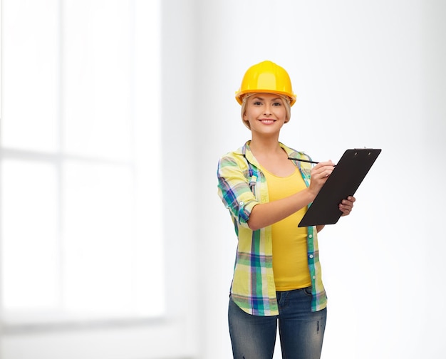 repair, construction and maintenance concept - smiling woman in helmet with clipboard