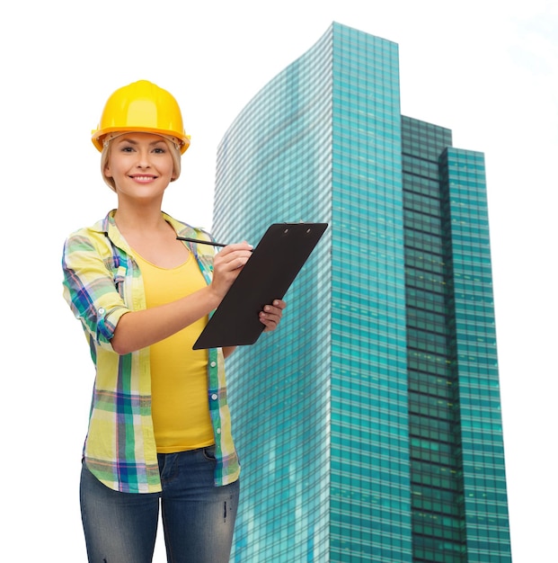 repair, construction and maintenance concept - smiling woman in helmet with clipboard