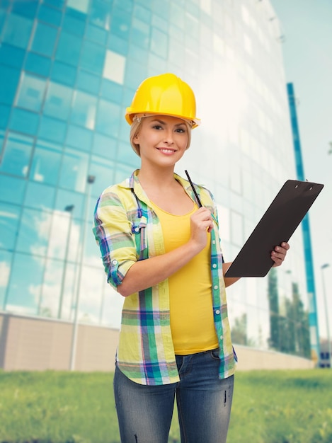 Photo repair, construction and maintenance concept - smiling woman in helmet with clipboard