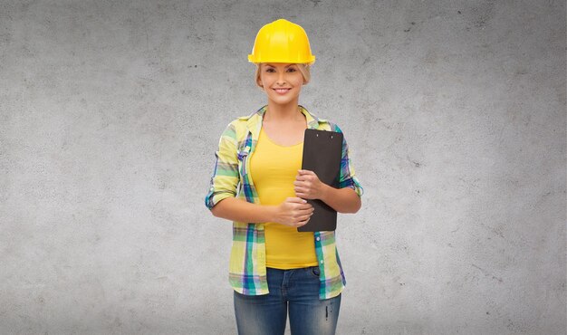 repair, construction and maintenance concept - smiling woman in helmet with clipboard