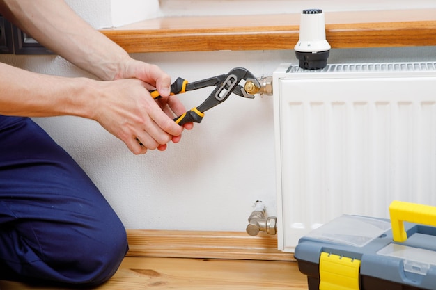 Repair heating radiator closeup man repairing radiator with wrench Removing air from the radiator