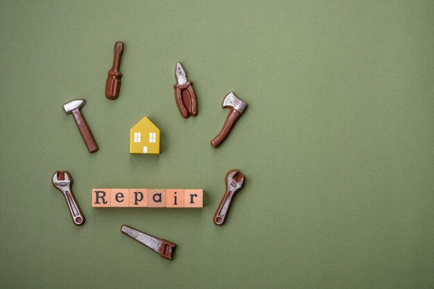 Repair or home improvement tools and a house model on a plain background