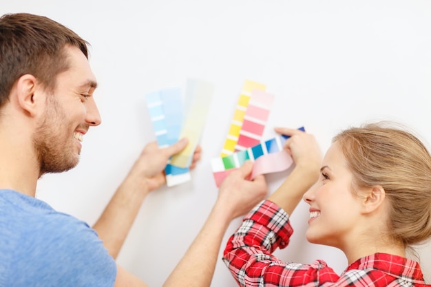 repair, interior design, building, renovation and home concept - smiling couple looking at color samples at home