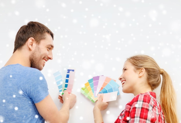 repair, interior design, building, renovation and people concept - smiling couple selecting color from samples at home