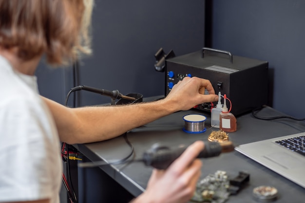 Repair, microcircuit. Strong male hands soldering making microcircuit in workshop with help of devices, no face