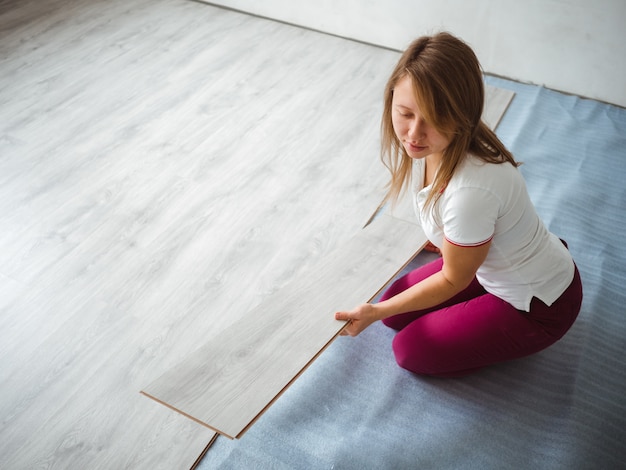 The repair process in the apartment. Girl holding a laminate board