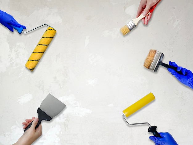 Repair and remodeling concept hands with a brush paint roller spatula and other tools for repair white background copy space