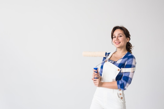 Riparazione, ristrutturazione, nuova casa e concetto di persone - la bella donna dipinge il muro durante la ristrutturazione con lo spazio della copia