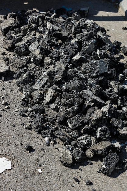 Riparazione del manto stradale un mucchio di pietre fatte di vecchio asfalto si trova sulla strada sfondo astratto con texture