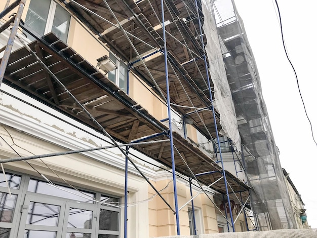 Repair work on the facade of the building with the help of wooden scaffolding structures restoration