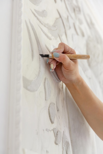 Repair workflow woman with chisel tool carves basrelief pattern on wall