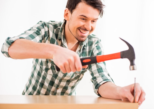 Repair young man hammer a nail at home.