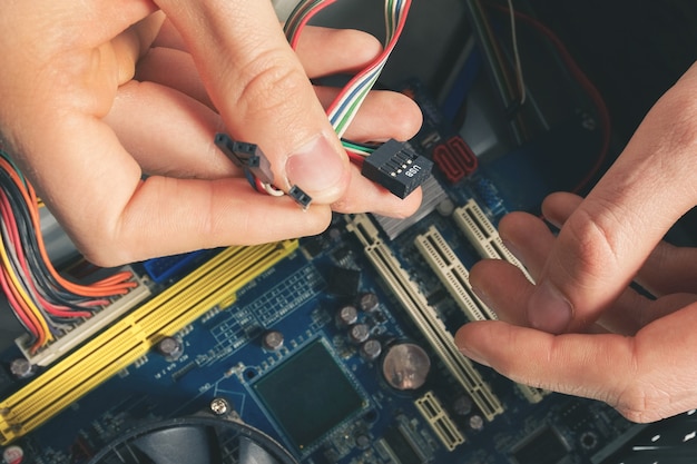 Il riparatore collega i fili nel computer. riparazione e smontaggio di apparecchiature informatiche.
