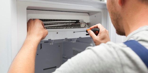 The repairer is fixing the freezer at home