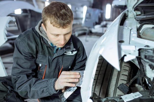 Repairing car body by puttying close up work after the accident by working sanding primer before painting. , The mechanic repair the car , Using plastic putty ,Prepare surface for spray painting.