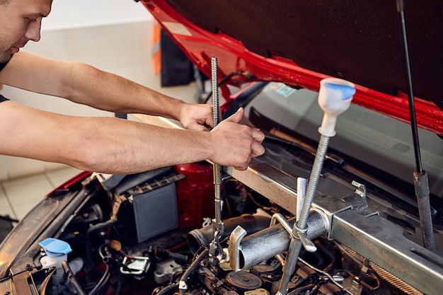 オートサービスセンターで車のエンジンを修理するガレージで働く自動車整備士
