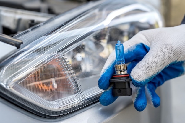 Repairman at autoshop show new car light bulb for replacement, headlamp in the surface