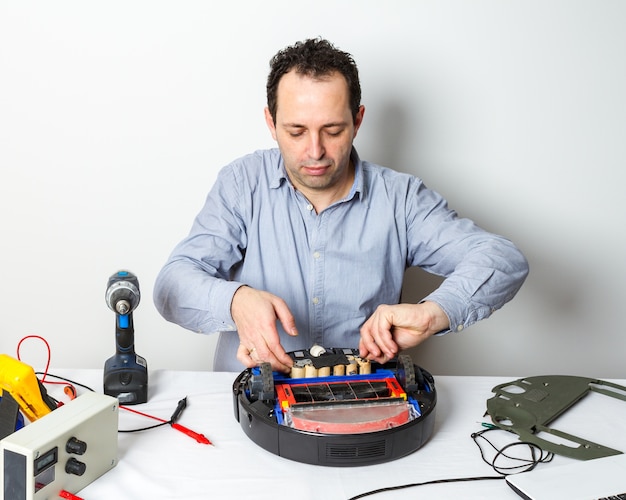 Repairman changing batteries on robotic vacuum cleaner