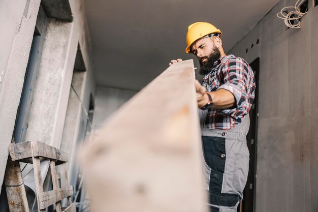 A repairman checking on wooden beam at building in construction process