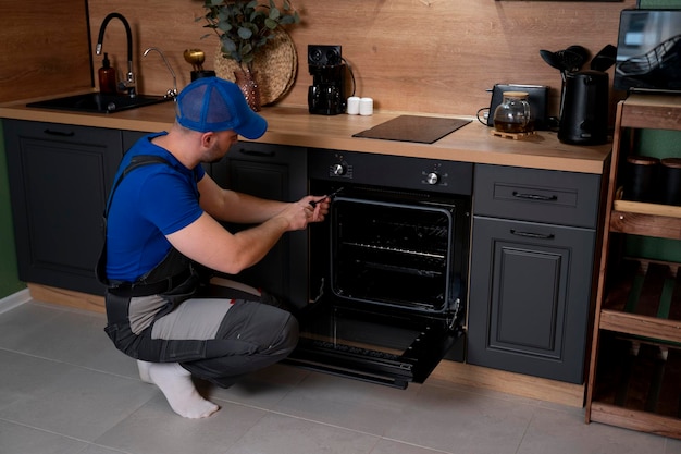 repairman examining oven a male worker repairing an oven in the kitchen room