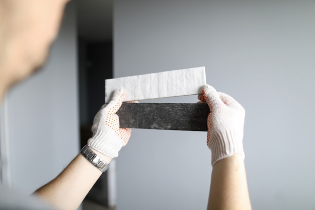 Repairman in gloves choosing right color of materials for interior details over grey walls background. Professional repairman during work concept