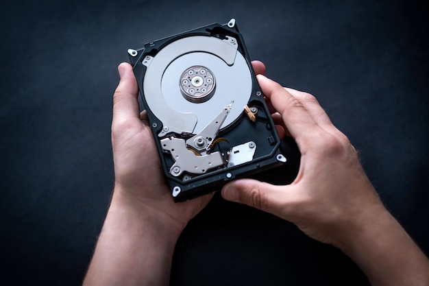 Repairman holding hard drive from computer in hands for fixing or diagnostics top view