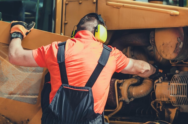 Photo repairman inspecting and adjusting engine in bulldozer