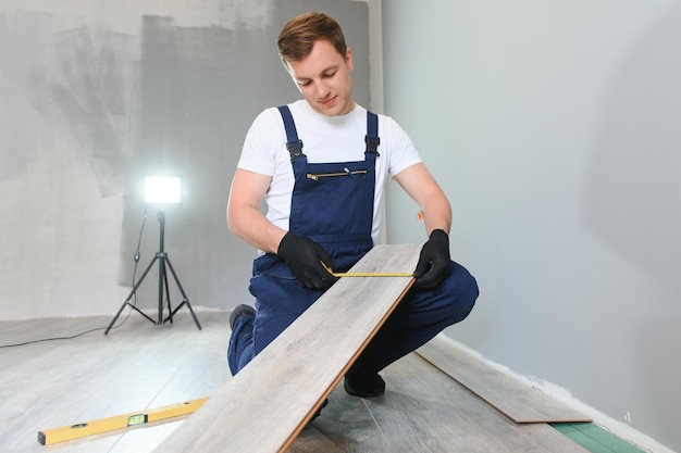 Repairman laying laminate flooring at home