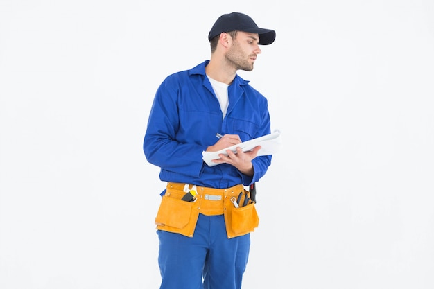 Repairman looking away while writing on clipboard