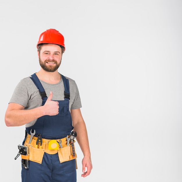 Photo repairman in overall and helmet showing thumb up