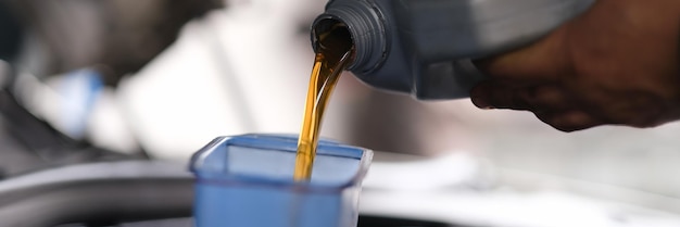 Photo repairman pouring motor oil into car engine closeup