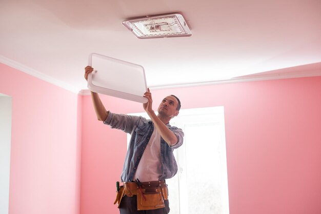 Repairman or professional electrician in workwear installing light spots