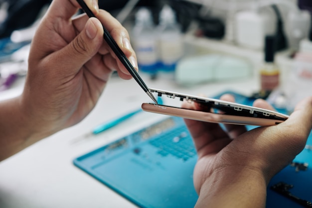 Repairman removing screen of smartphone