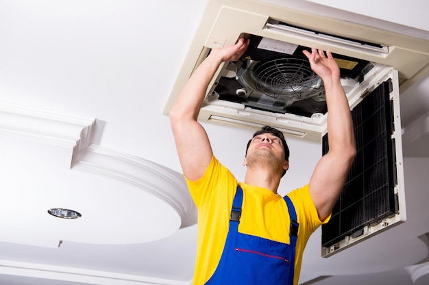 Photo repairman repairing ceiling air conditioning unit