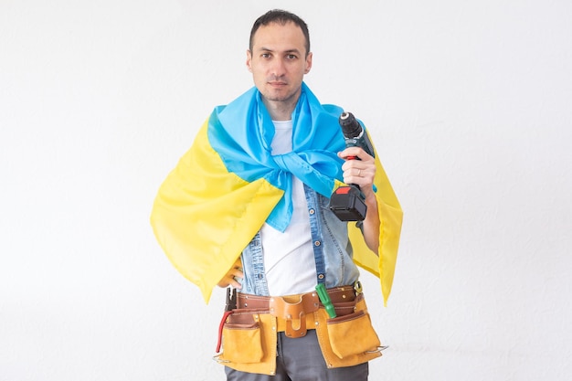 Ремонтник стоит с дрелью в руке и с флагом Украины