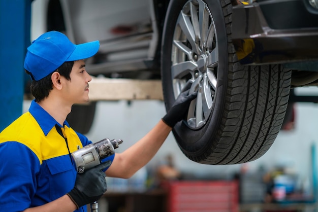 青い制服を着た自動車ガレージサービスの修理工と技術者が立ち上がり、工具を使って笑顔を見せる