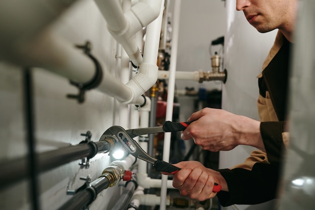Photo repairman using a tool to fix parts of pipes during work
