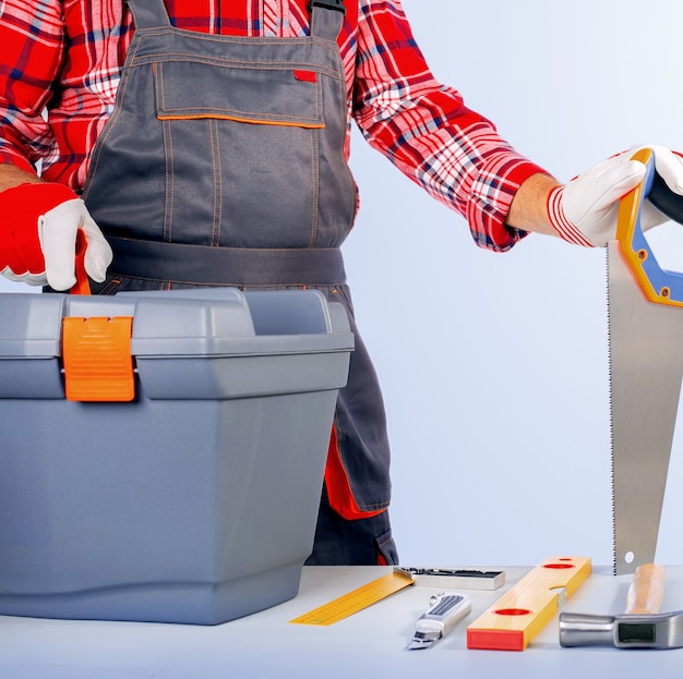 Repairman with toolbox against grey wall.