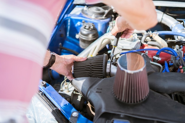 The repairman work with the car replacing the cylinder intake air filter