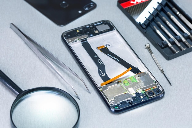 Photo repairman workplace with phone and tools on grey surface. mobile phone repair concept.