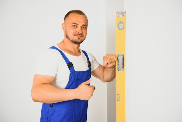 Reparateur controleert de vlakheid van de muur met behulp van een waterpas.