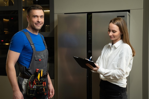 Reparateur toont vaste koelkast aan vrouw in keuken