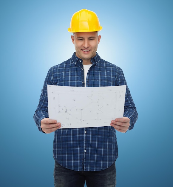 reparatie, bouw, bouw, mensen en onderhoudsconcept - glimlachende mannelijke bouwer of arbeider in helm met blauwdruk over blauwe achtergrond