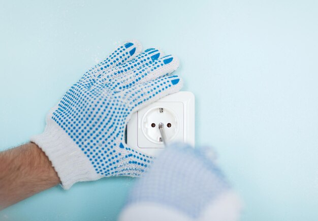 reparatie, bouw, elektriciteit en thuisconcept - close-up van man in handschoenen die nieuwe socket installeren