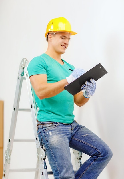 reparatie-, bouw- en huisconcept - lachende man in beschermende helm met klembord