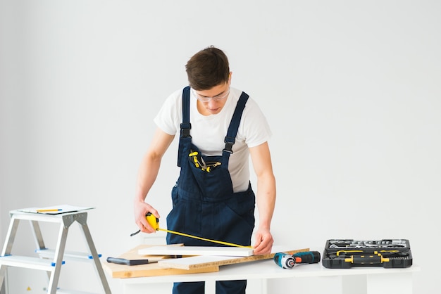 Reparatie, constructie en bouwconcept - gelukkig lachend mannelijke werknemer of bouwer in bril bij nieuw huis op de achtergrond
