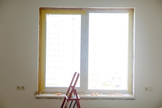 Foto reparatie in de hellingen van het raam. het proces van het aanbrengen van een laag pleister op de zijkanten van het raam.